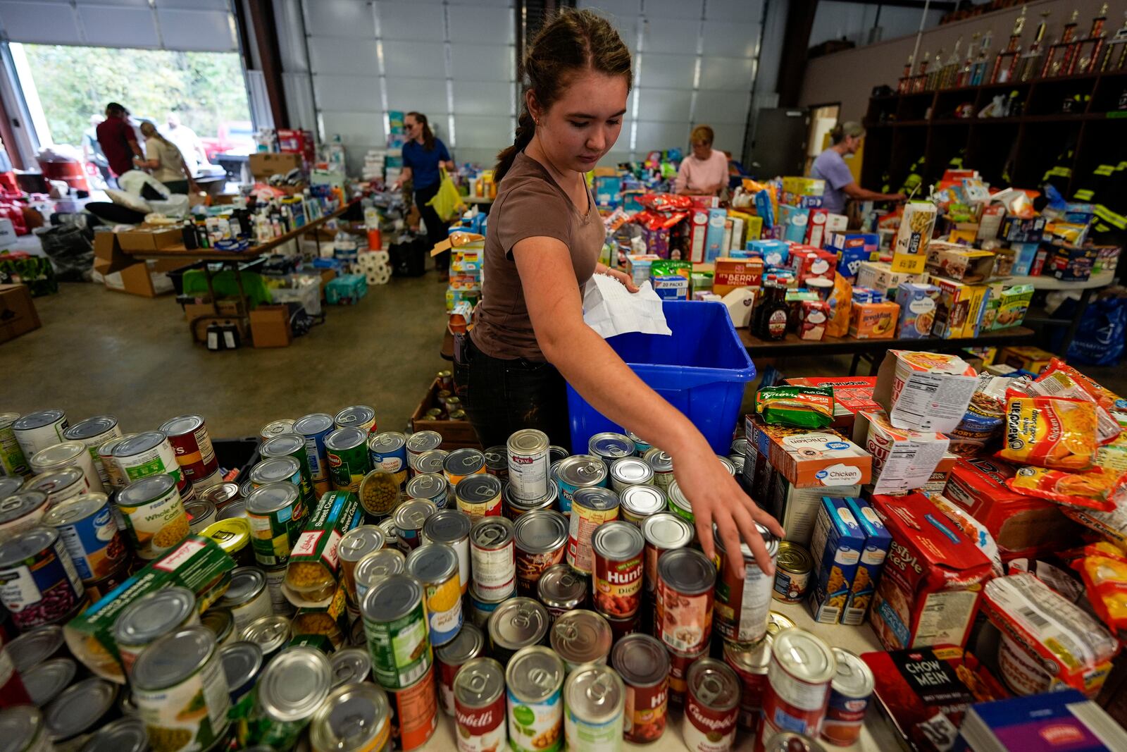 A volunteer gathers food for families at the volunteer fire station in the aftermath of Hurricane Helene, Thursday, Oct. 3, 2024, in Pensacola, N.C. (AP Photo/Mike Stewart)