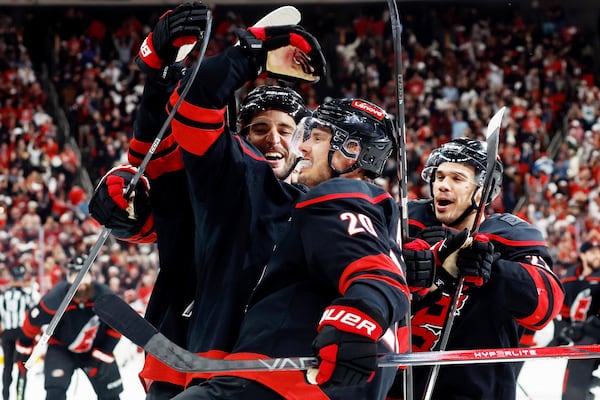 Carolina Hurricanes' Sebastian Aho, center, celebrates with teammates Shayne Gostisbehere, left, and Logan Stankoven (22) after Aho's game-winning goal during the second overtime period of Game 5 of an NHL hockey first-round playoff series against the New Jersey Devils in Raleigh, N.C., Tuesday, April 29, 2025. (AP Photo/Karl DeBlaker)