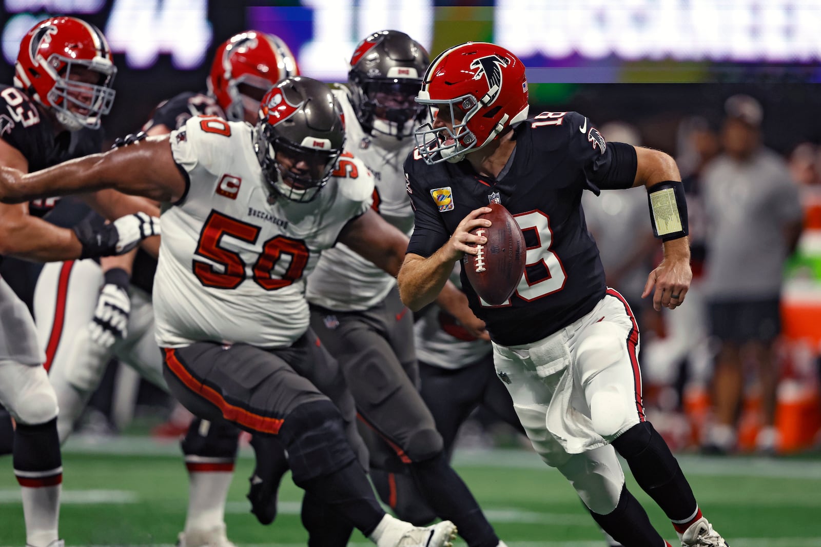 Atlanta Falcons quarterback Kirk Cousins (18) scrambles away from Tampa Bay Buccaneers defensive tackle Vita Vea (50) during the first half of an NFL football game Thursday, Oct. 3, 2024, in Atlanta. (AP Photo/Butch Dill)