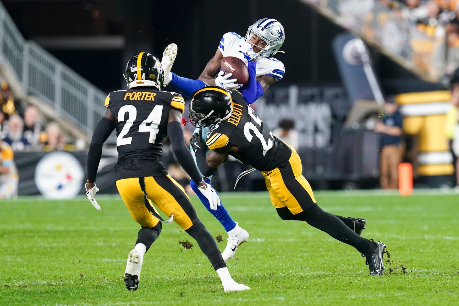 Dallas Cowboys wide receiver Jalen Brooks, top, catches a pass while being hit by Pittsburgh Steelers safety DeShon Elliott (25) during the first half of an NFL football game, Sunday, Oct. 6, 2024, in Pittsburgh. Steelers' Joey Porter Jr. (24) looks on. (AP Photo/Matt Freed)