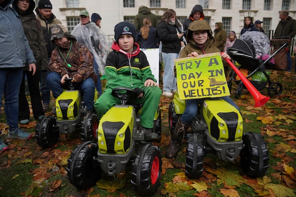 From left, Eddie England, Seth James and Tilly James, attend a farmers protest, urging the government to change course over its inheritance tax plans, in London, Tuesday, Nov. 19, 2024. (AP Photo/Kin Cheung)