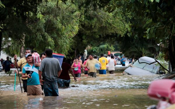 FILE - Residents walk past inundated vehicles in the flooded streets of Planeta, Honduras, Nov. 6, 2020, in the aftermath of Hurricane Eta. (AP Photo/Delmer Martinez, File)