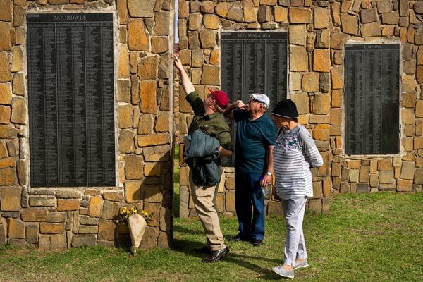 Visitors at the Nampo agricultural fair, one of the largest in the southern hemisphere, check names on the wall of remembrance, a tribute to farmers killed since 1961, near Bothaville, South Africa, May 15, 2025. (AP Photo/Jerome Delay)