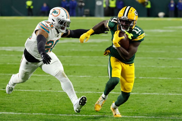 Green Bay Packers wide receiver Jayden Reed (11) runs from Miami Dolphins linebacker Jordyn Brooks (20) during a 12-yard touchdown reception in the first half of an NFL football game Thursday, Nov. 28, 2024, in Green Bay, Wis. (AP Photo/Mike Roemer)