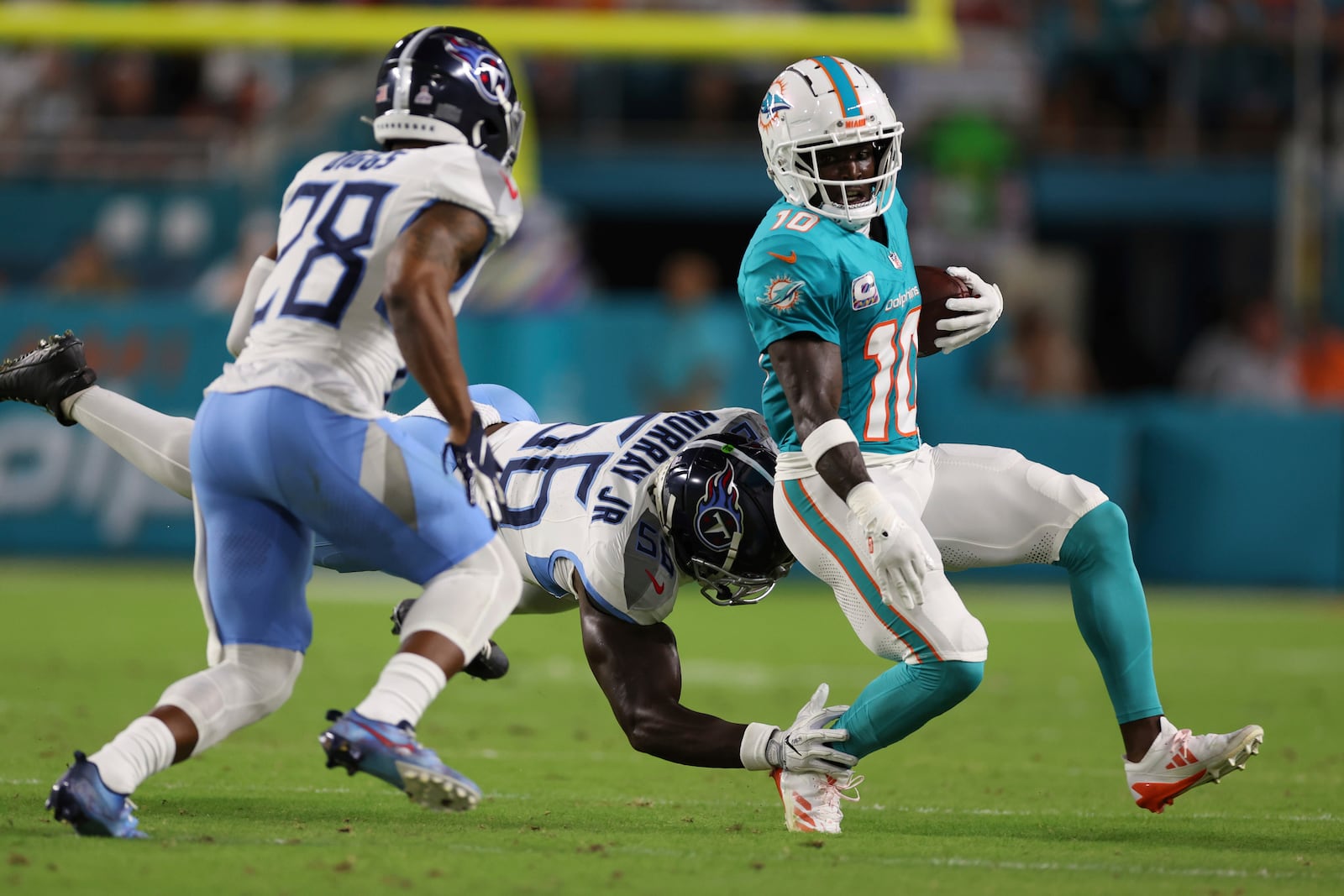 Tennessee Titans linebacker Kenneth Murray Jr. (56) grabs Miami Dolphins wide receiver Tyreek Hill (10) during the first half of an NFL football game, Monday, Sept. 30, 2024, in Miami Gardens, Fla. (AP Photo/Brennan Asplen)