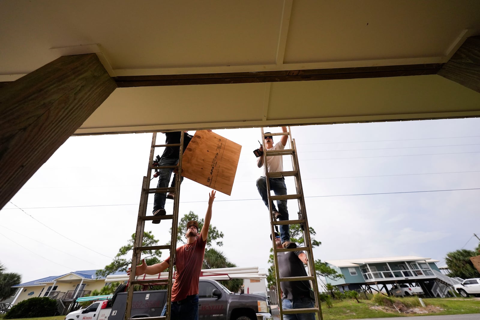 Jerry McCullen, top of ladder left, and Carson Baze, top of ladder right, put plywood over the windows of a house ahead of Hurricane Helene, expected to make landfall Thursday evening, in Alligator Point, Fla., Wednesday, Sept. 25, 2024. (AP Photo/Gerald Herbert)