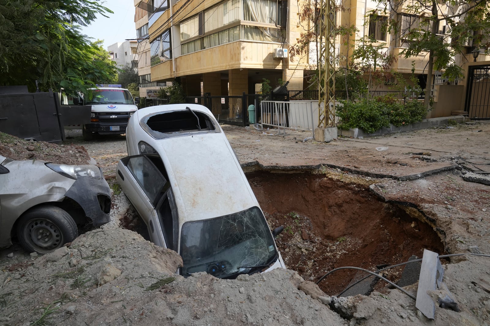 A car sits in a crater in Beirut's southern suburbs, Saturday, Sept. 28, 2024. (AP Photo/Hussein Malla)