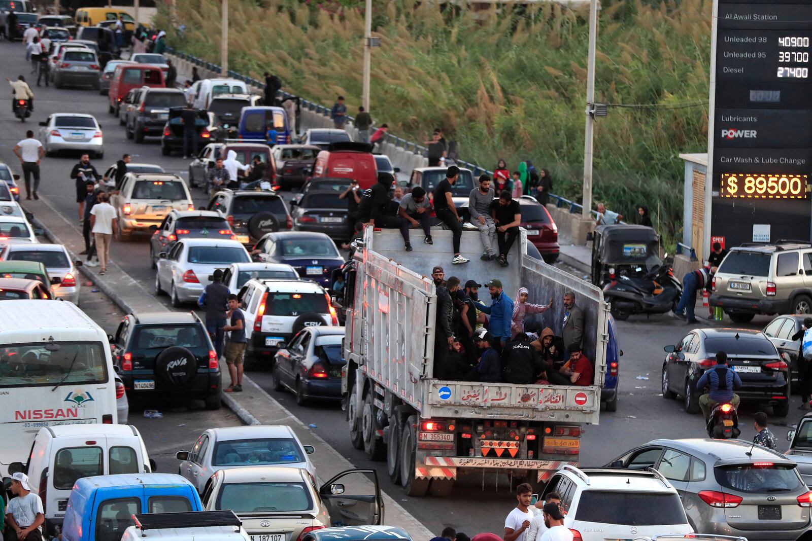 Lebanese citizens who fled on the southern villages amid ongoing Israeli airstrikes Monday, sit on their cars at a highway that links to Beirut city, in the southern port city of Sidon, Lebanon, Tuesday, Sept. 24, 2024. (AP Photo/Mohammed Zaatari)