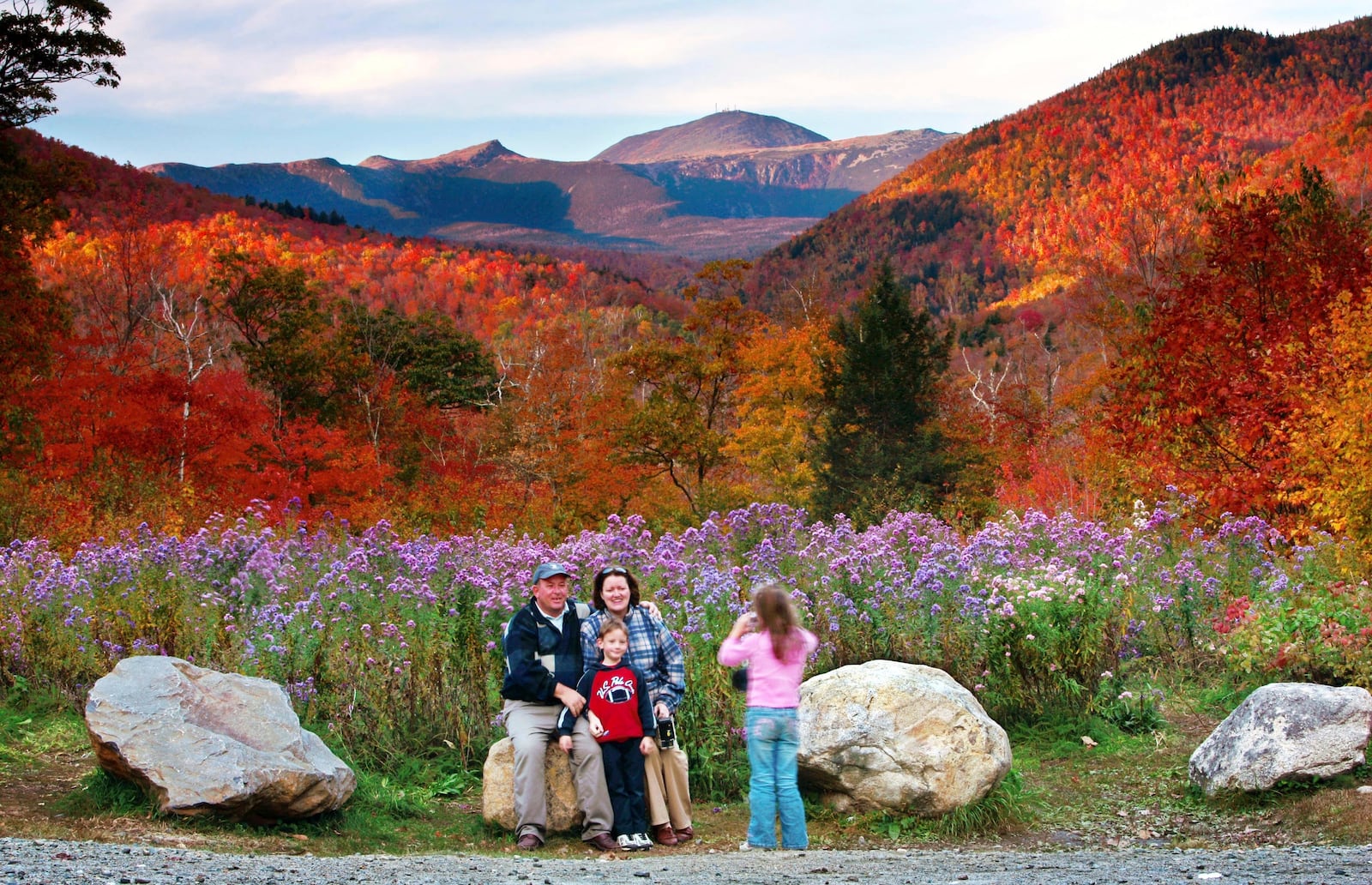 FILE - Wildflowers, fall foliage and the 6,288-foot Mt. Washington serve as a backdrop for Jim and Kathleen Gannon and their son James as their daughter Katarina snaps a picture at Crawford Notch State Park in New Hampshire, Oct. 6, 2006. (AP Photo/Robert F. Bukaty, File)