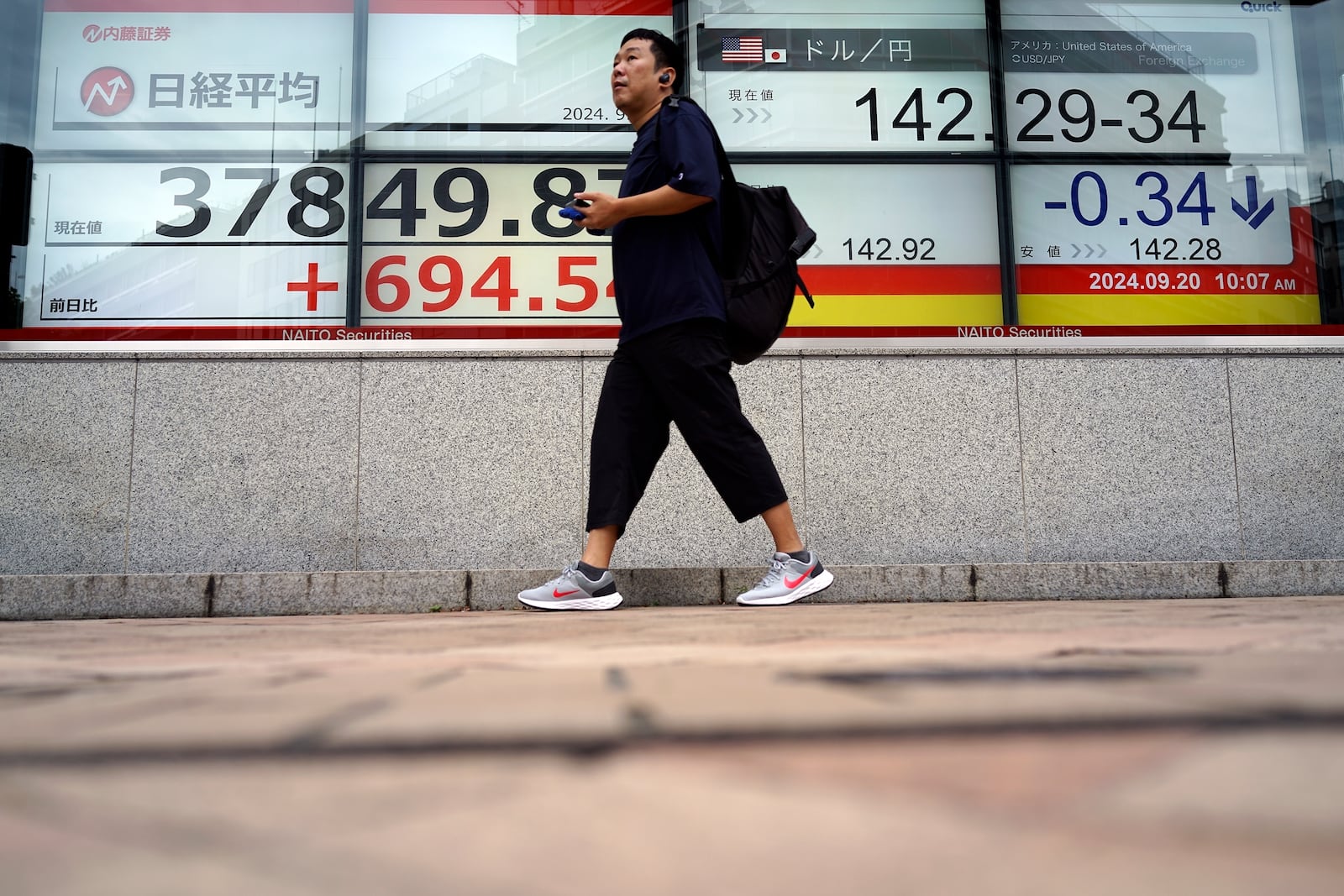 A person walks in front of an electronic stock board showing Japan's Nikkei index and Japanese Yen exchange rate at a securities firm Friday, Sept. 20, 2024, in Tokyo. (AP Photo/Eugene Hoshiko)