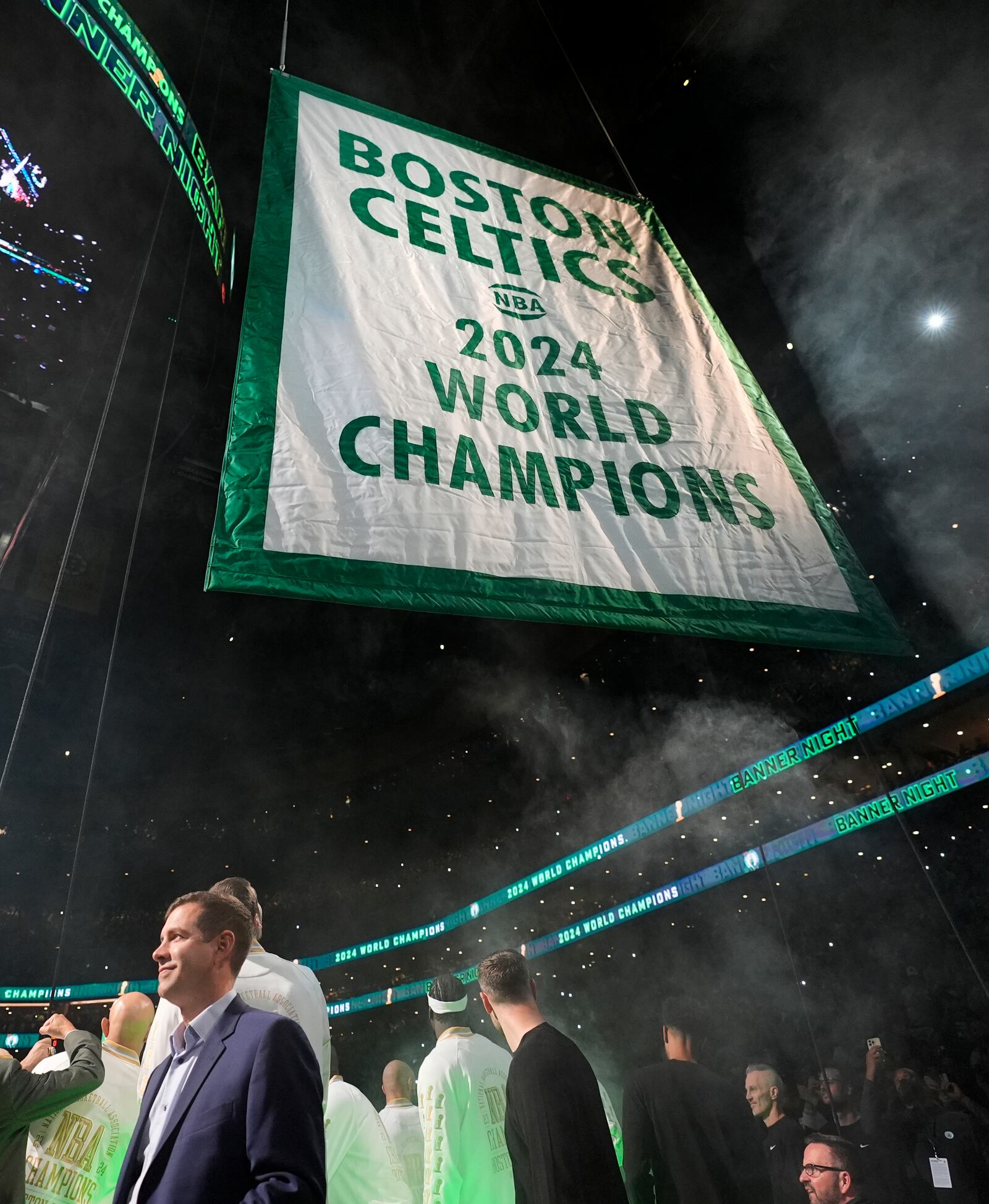 Boston Celtics general manager Brad Stevens, left, looks on as the 2024 World Championship banner is raised prior to an NBA basketball game against the New York Knicks, Tuesday, Oct. 22, 2024, in Boston. (AP Photo/Charles Krupa)