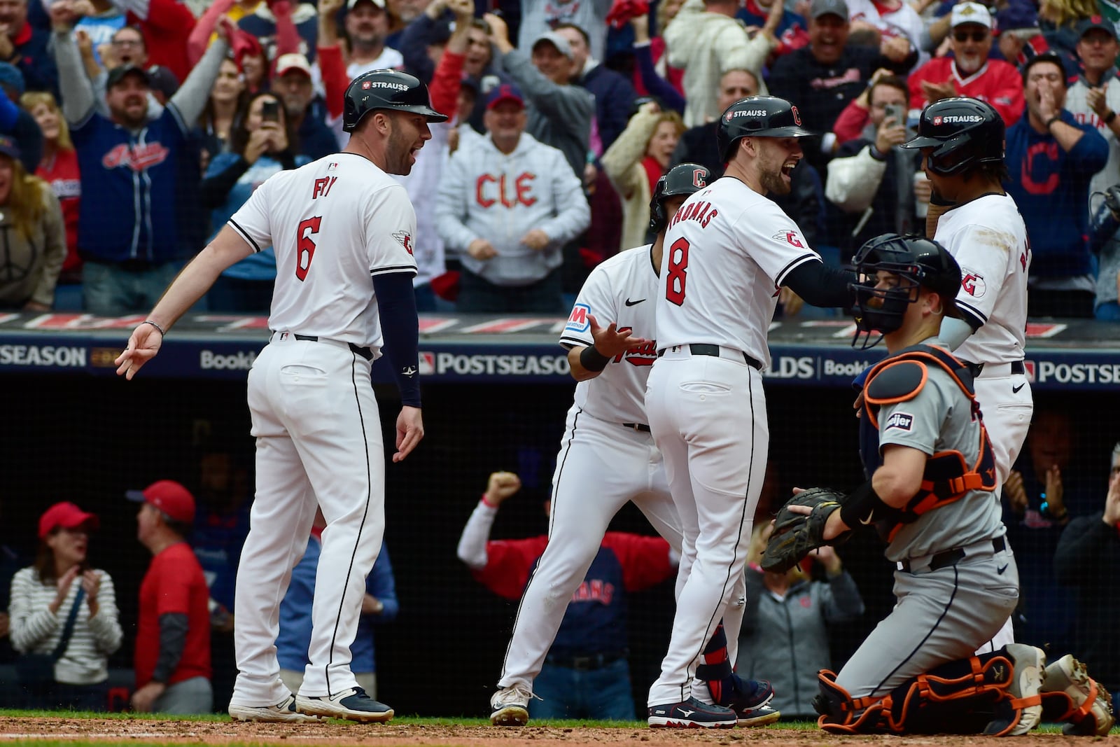 Cleveland Guardians' Lane Thomas (8) celebrates with teammates, from left, David Fry, Steven Kwan, partially hidden, and Jose Ramirez, right, behind Detroit Tigers catcher Jake Rogers, after hitting a grand slam in the fifth inning during Game 5 of baseball's American League Division Series, Saturday, Oct. 12, 2024, in Cleveland. (AP Photo/Phil Long)