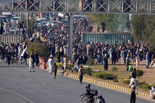 Supporters of imprisoned former premier Imran Khan's Pakistan Tehreek-e-Insaf party, gather to remove shipping container to clear way for their rally demanding Khan's release, in Islamabad, Pakistan, Tuesday, Nov. 26, 2024. (AP Photo/Anjum Naveed)