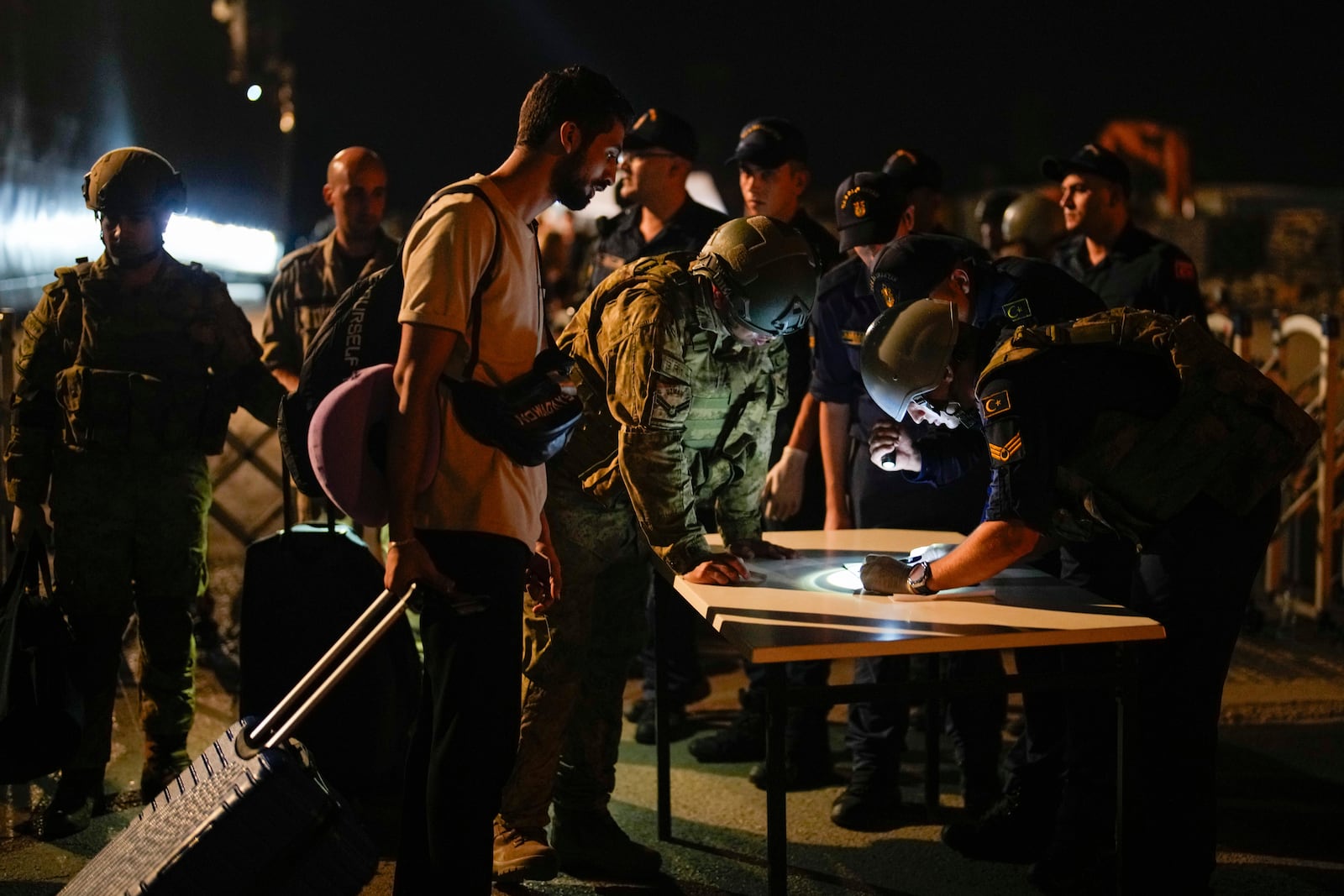 Turkish security officials verify the travel documents of citizens before boarding Turkish military ships to evacuate them from Lebanon to Turkey in Beirut port on Wednesday, Oct. 9, 2024. (AP Photo/Emrah Gurel)