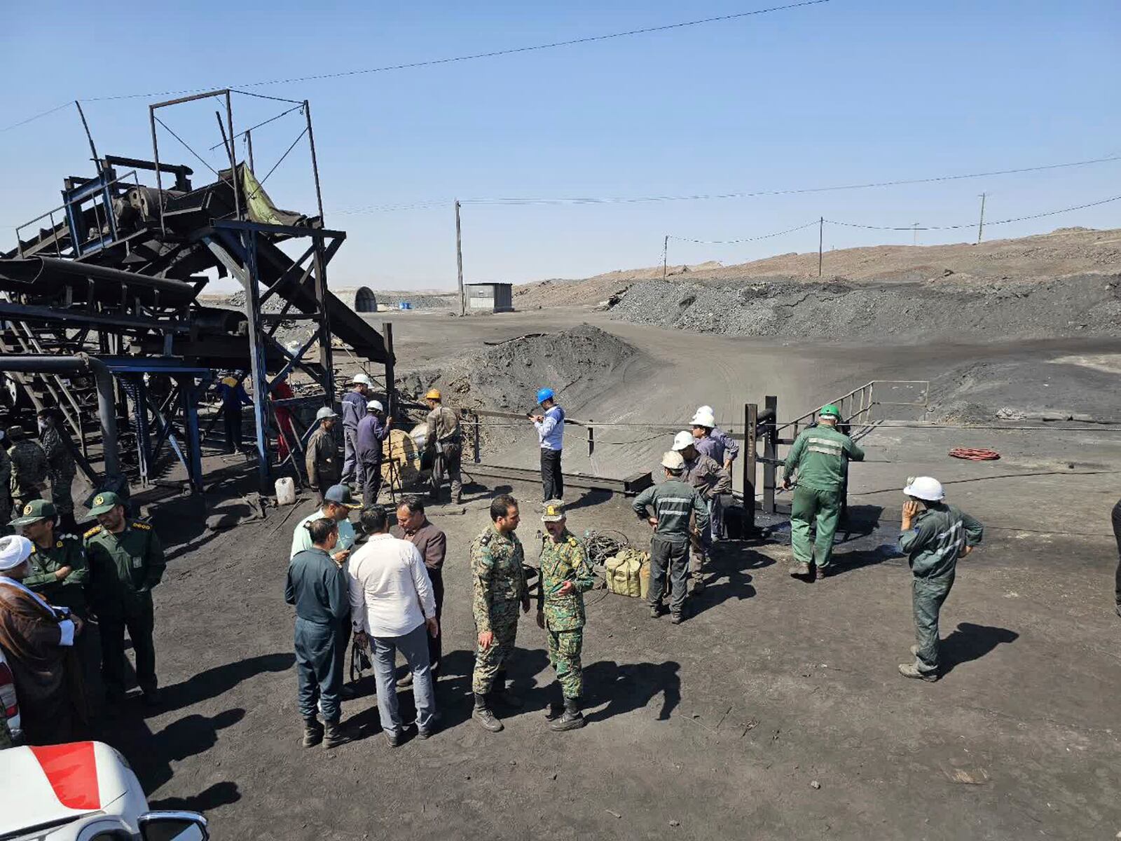 In this photo released by Iranian Red Crescent Society, miners and police officers gather around the site of a coal mine where methane leak sparked an explosion on Saturday, in Tabas, some 335 miles (540 kilometers) southeast of the capital Tehran, Iran, Sunday, Sept. 22, 2024. (Iranian Red Crescent Society, via AP)