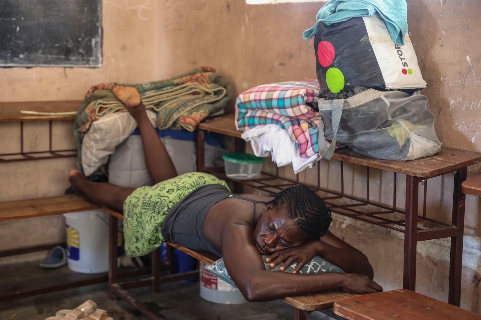 A person displaced by armed gang attacks rests at the Antoinette Dessalines National School, a makeshift shelter, in Saint-Marc, Haiti, Sunday, Oct. 6, 2024. (AP Photo/Odelyn Joseph)