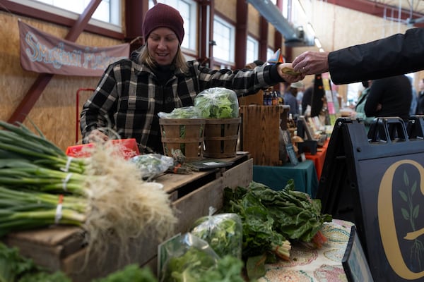 Courtney Klee, an employee of Growing Family Farms, handles a purchase at the Brighton Farmers Market on Sunday, March 23, 2025, in Brighton, N.Y. (Caitlyn Daproza via AP)