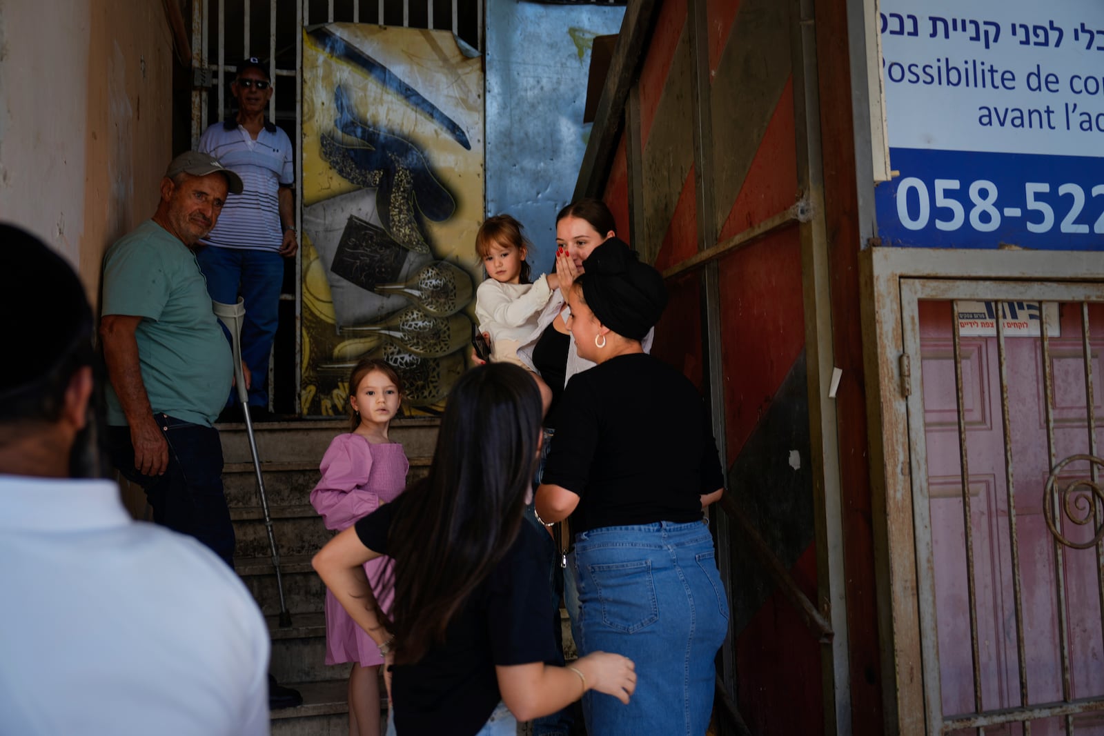 People take cover as a siren sounds a warning of incoming rockets fired from Lebanon, in Safed, northern Israel, Thursday, Sept. 26, 2024. (AP Photo/Ariel Schalit)