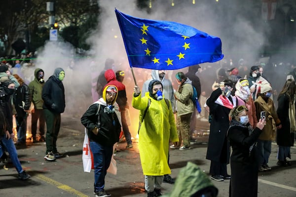 A protester waves an European Union flag during a rally outside the parliament to protest the governments' decision to suspend negotiations on joining the European Union for four years in Tbilisi, Georgia, early Saturday, Nov. 30, 2024. (AP Photo/Zurab Tsertsvadze)