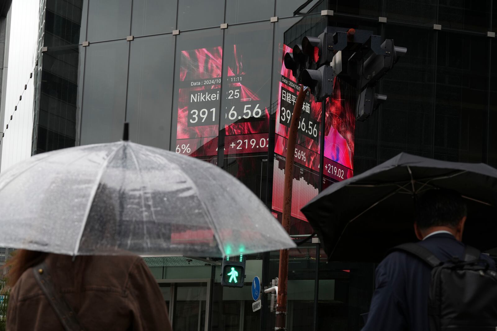 People walk in front of an electronic stock board showing Japan's Nikkei index at a securities firm, Wednesday, Oct. 9, 2024, in Tokyo. (AP Photo/Eugene Hoshiko)