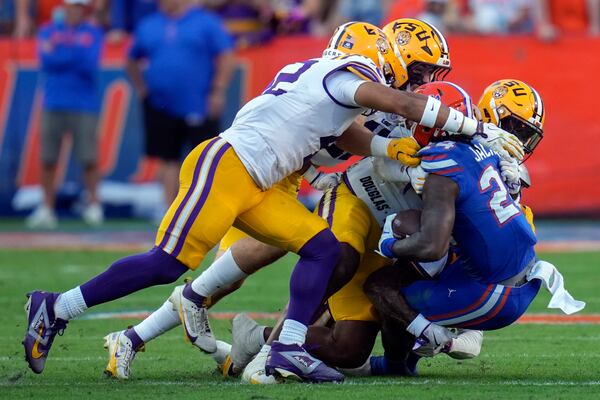 Florida running back Ja'Kobi Jackson, right, is swarmed by the LSU defense on a run during the first half of an NCAA college football game, Saturday, Nov. 16, 2024, in Gainesville, Fla. (AP Photo/John Raoux)