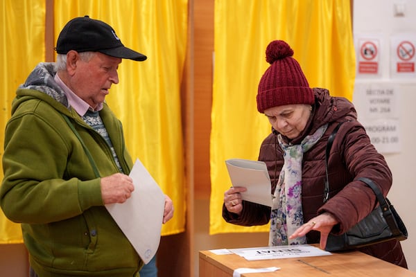 People prepare to cast their vote in the country's parliamentary elections, in Mogosoaia, Romania, Sunday, Dec. 1, 2024. (AP Photo/Andreea Alexandru)