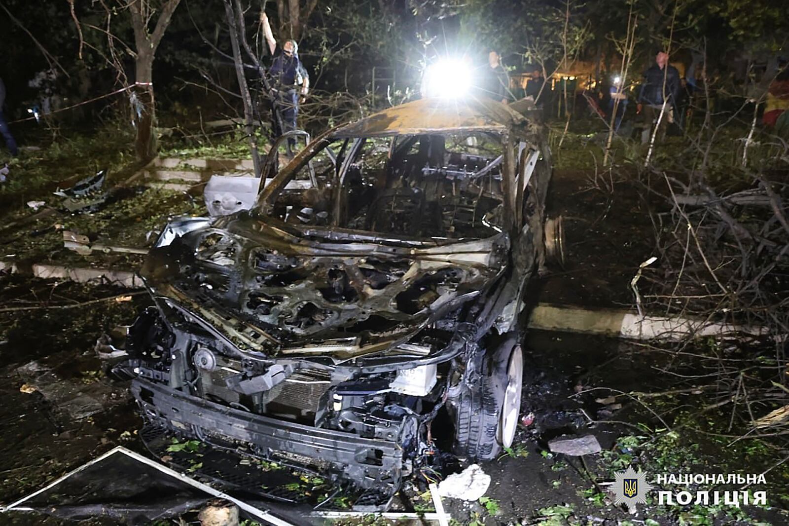 A light is shone on a damaged car after a Russian strike on a residential building in Kharkiv, Ukraine early Sunday Sept. 22, 2024. (Ukrainian National Police via AP)