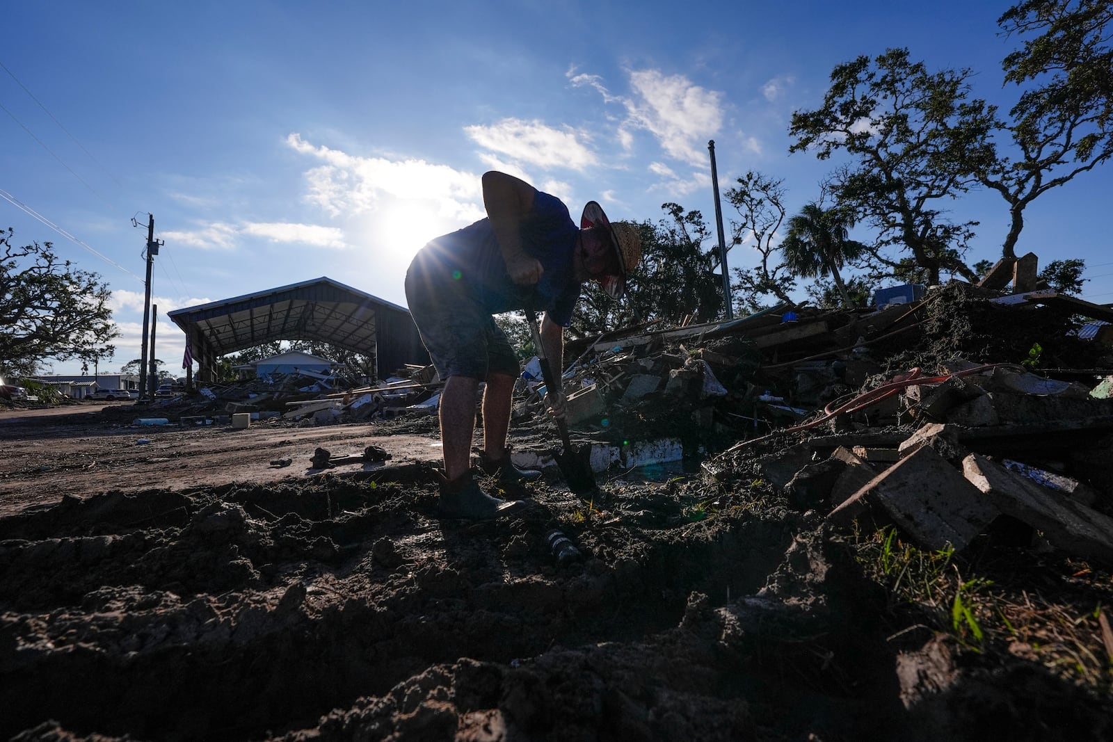 Chris Jordan, maintenance manager for Horseshoe Beach, tries to find a water shutoff valve amid the rubble of the destroyed city hall in the aftermath of Hurricane Helene, in Horseshoe Beach, Fla., Sunday, Sept. 29, 2024. (AP Photo/Gerald Herbert)