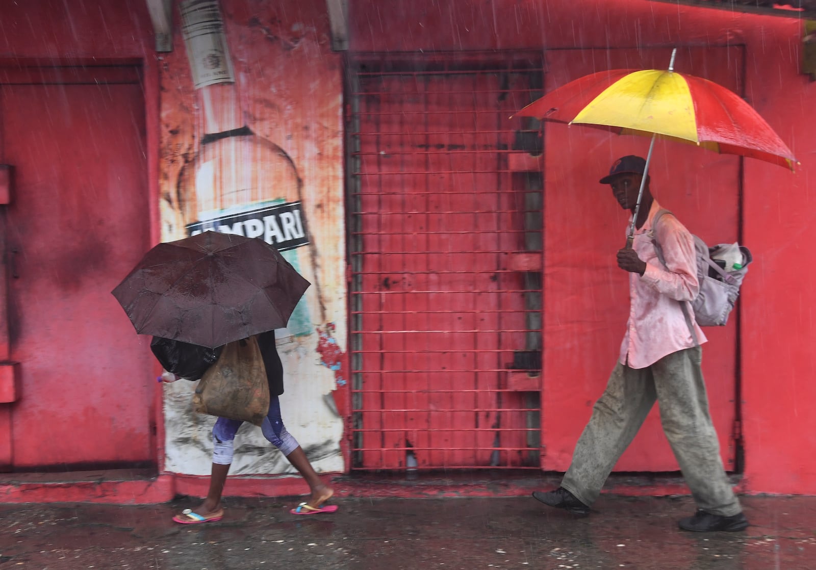 Pedestrians walk during rains brought on by tropical storm Rafael in Kingston, Jamaica, Tuesday, Nov. 5, 2024. (AP Photo/Collin Reid)