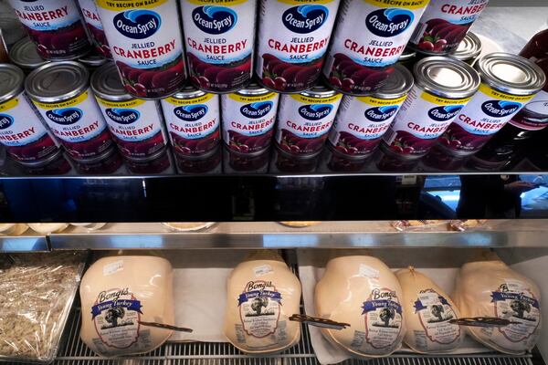 Cans of cranberry sauce line a turkey display case at Bongi's Turkey Roost in advance of the Thanksgiving holiday, Tuesday, Nov. 22, 2022, in Duxbury, Mass. (AP Photo/Charles Krupa)