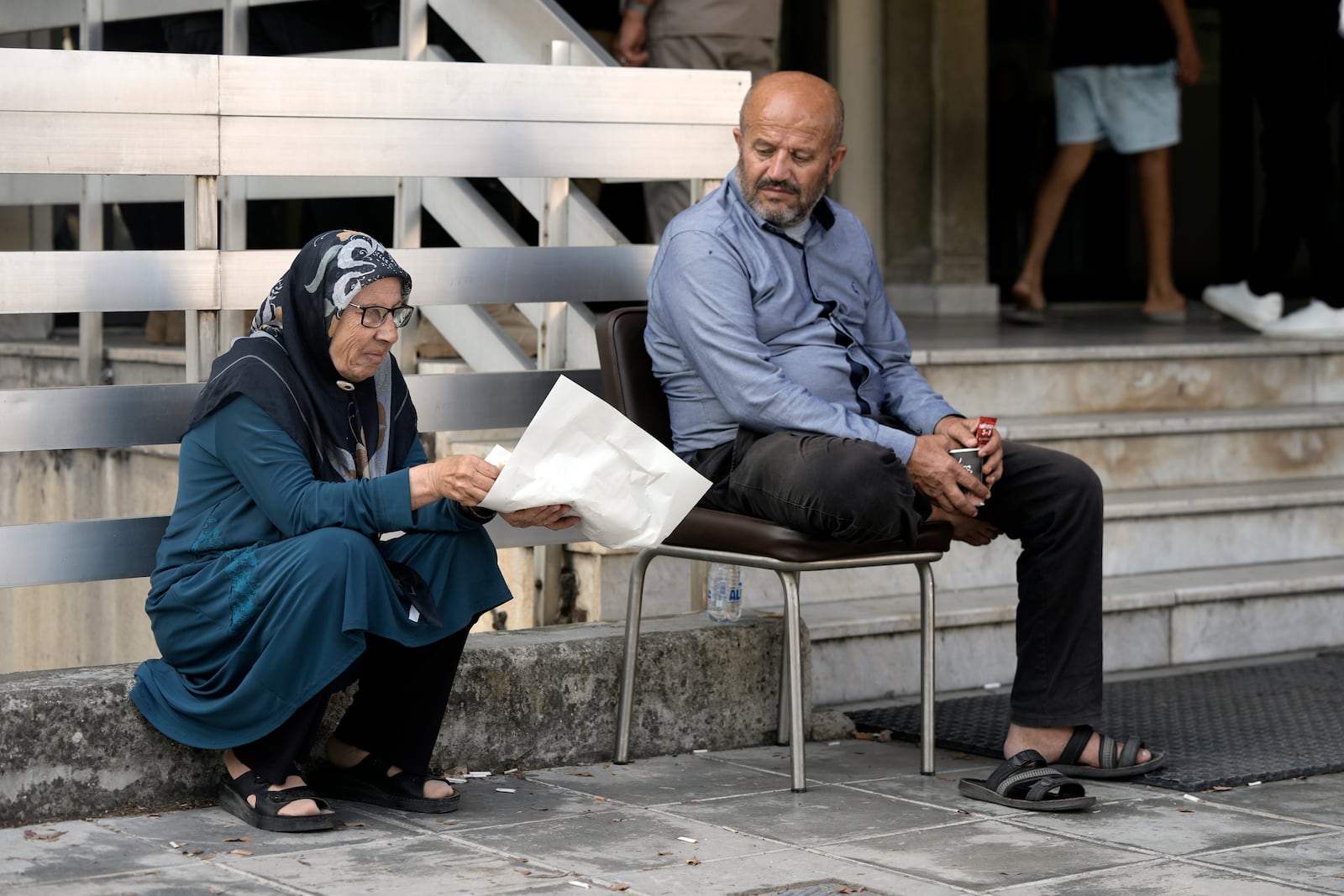 A couple sit outside a school turned into a shelter in Beirut, after fleeing the Israeli airstrikes in the southern village of Houla, Tuesday, Sept. 24, 2024. (AP Photo/Bilal Hussein)