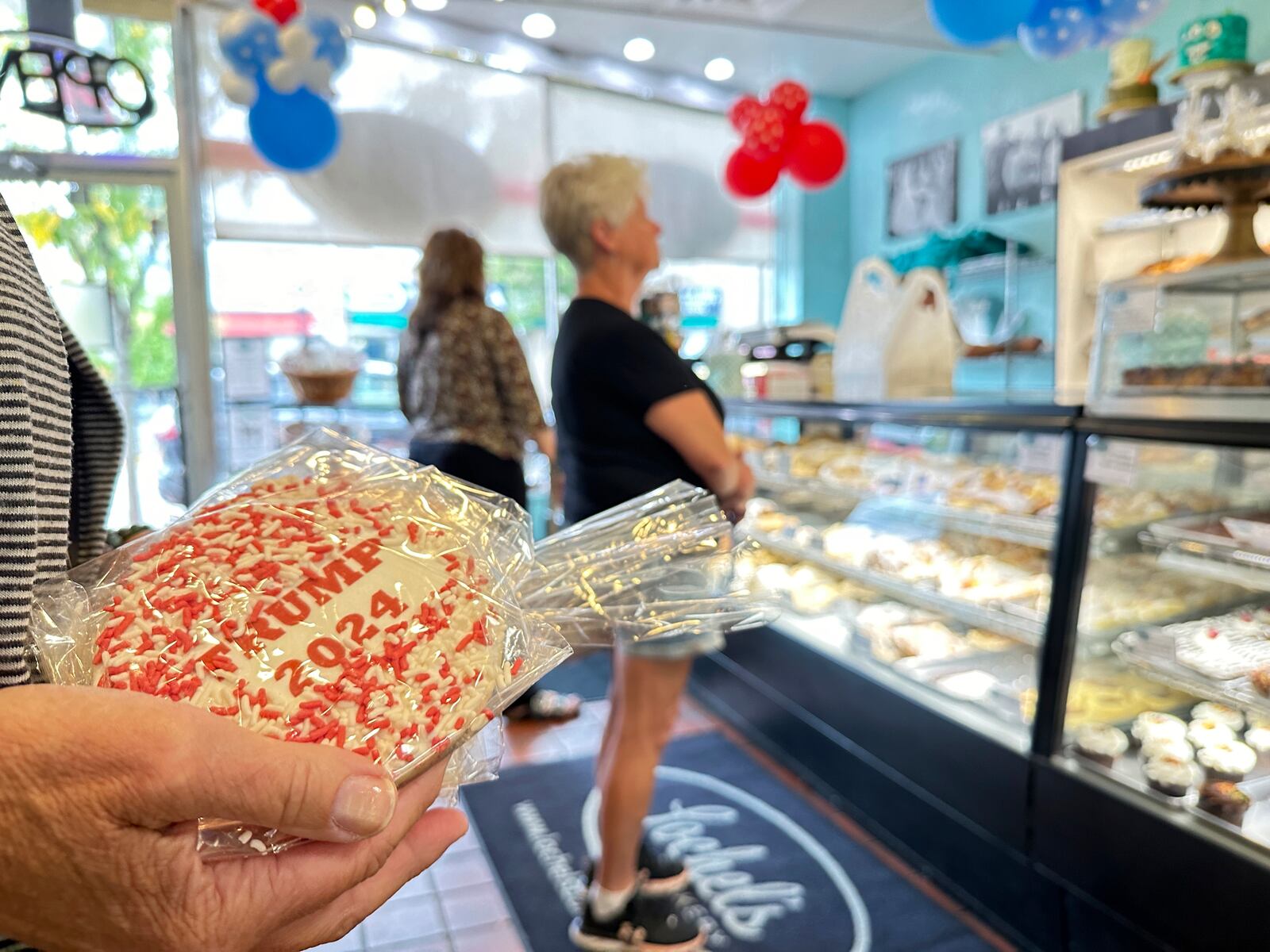 A customer holds a sugar cookie with a Trump 2024 label on at Lochel's Bakery in the town of Hatboro in suburban Philadelphia, Tuesday, Sept. 24, 2024. Lochel's Bakery started the election cookie poll in 2008 as a joke between the third-generation bakery owners and their local customers. (AP Photo/Tassanee Vejpongsa)