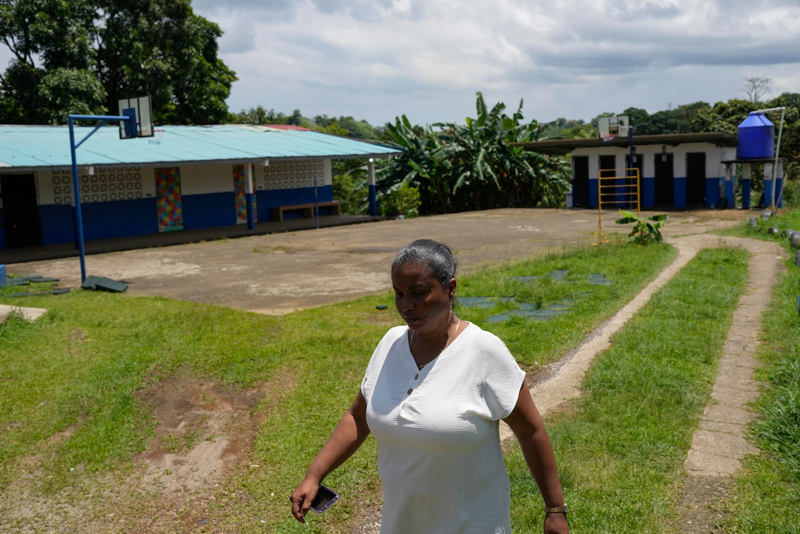 La Represa School Principal Zuleyka Ramirez walks through a yard in the school, which closes when the water supply is cut off, in Colon, Panama, Monday, Sept. 2, 2024. Under a proposed plan to dam the nearby Indio River and secure the Panama Canal's uninterrupted operation, the community could gain more reliable access to water. (AP Photo/Matias Delacroix)