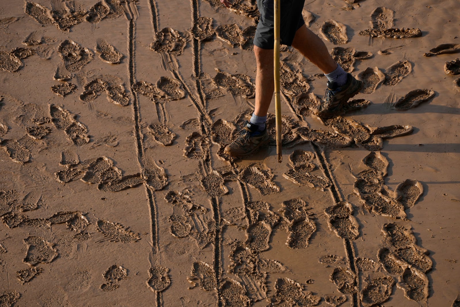 A man walks on a mud-covered road after flooding in Valencia, Spain, Thursday, Oct. 31, 2024. (AP Photo/Manu Fernandez)