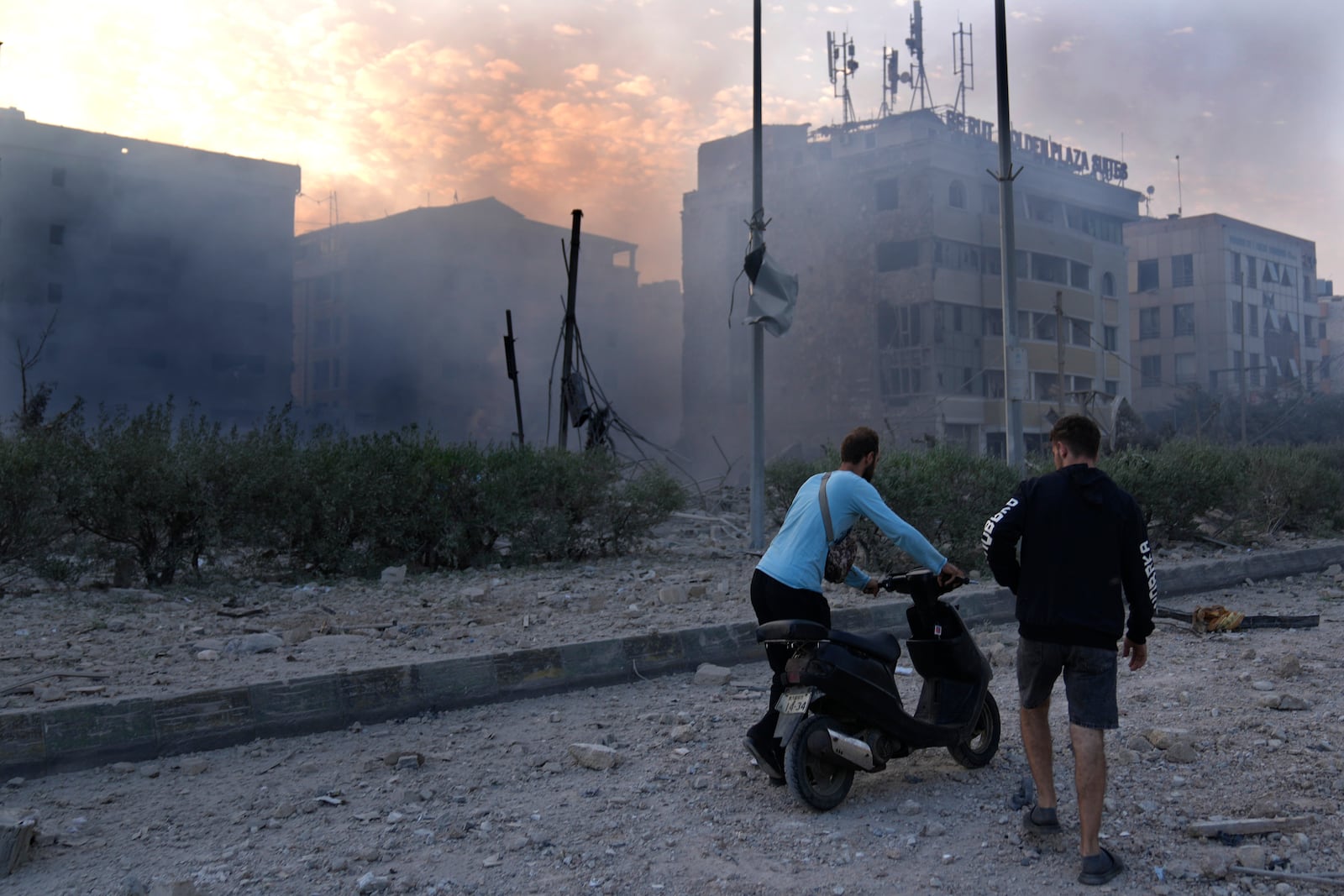 A man pushes his scooter in front of destroyed buildings hit by Israeli airstrikes in Dahiyeh, Beirut, Lebanon, Sunday, Oct. 6, 2024. (AP Photo/Hussein Malla)