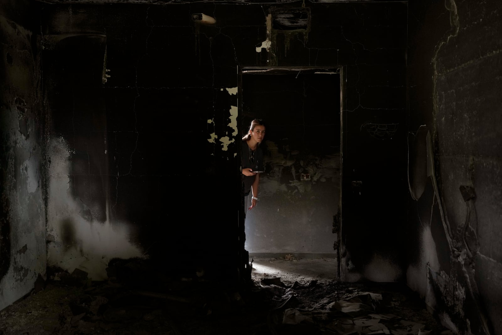 A woman looks at a battle-scarred home at the Kibbutz Be'eri, an Israeli communal farm on the Gaza border, as Israel marks the one-year anniversary of the Hamas attack on Israel on Monday, Oct. 7, 2024. (AP Photo/Ohad Zwigenberg)