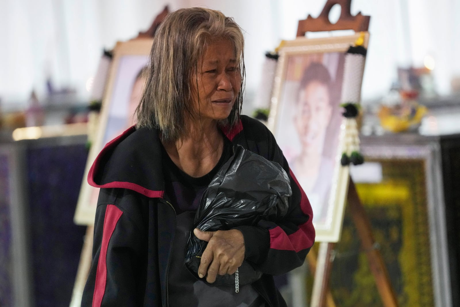 A relative of a victim of school bus fire cries at Wat Khao Phraya Sangkharam School Lan Sak, Uthai Thani province, Thailand, Thursday, Oct. 3, 2024. (AP Photo/Sakchai Lalit)