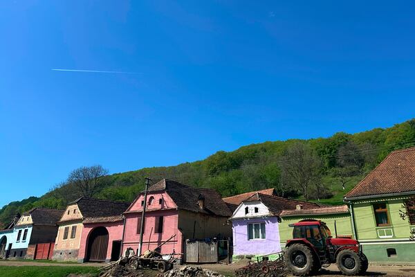 A tractor is parked outside a row of houses in the village of Floresti, in Romania's central Transylvania region, Thursday, April 24, 2025. (AP Photo/Stephen McGrath)