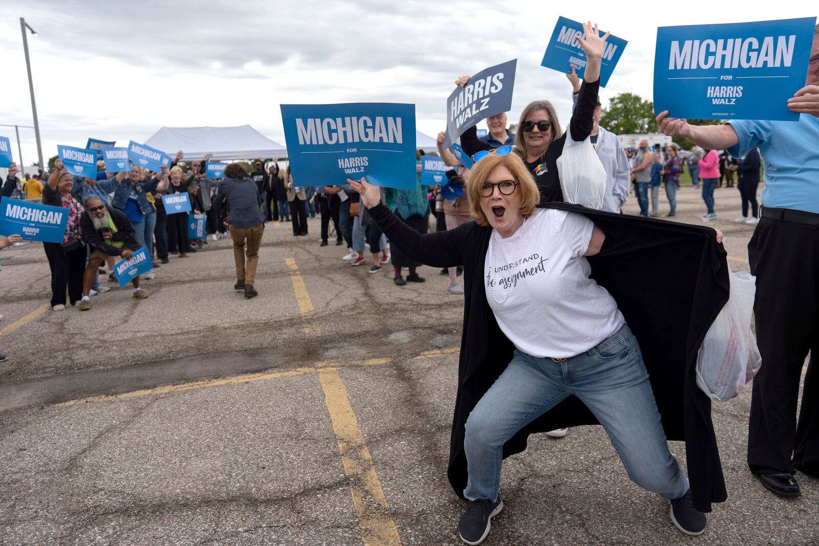 Supporters of Democratic presidential nominee Vice President Kamala Harris, including Carrie Charlick in the white shirt at right, cheer with members of the Harris campaign staff as they line up to enter the Dort Financial Center for a rally in Flint, Mich., Friday, Oct. 4, 2024. (AP Photo/Carolyn Kaster)