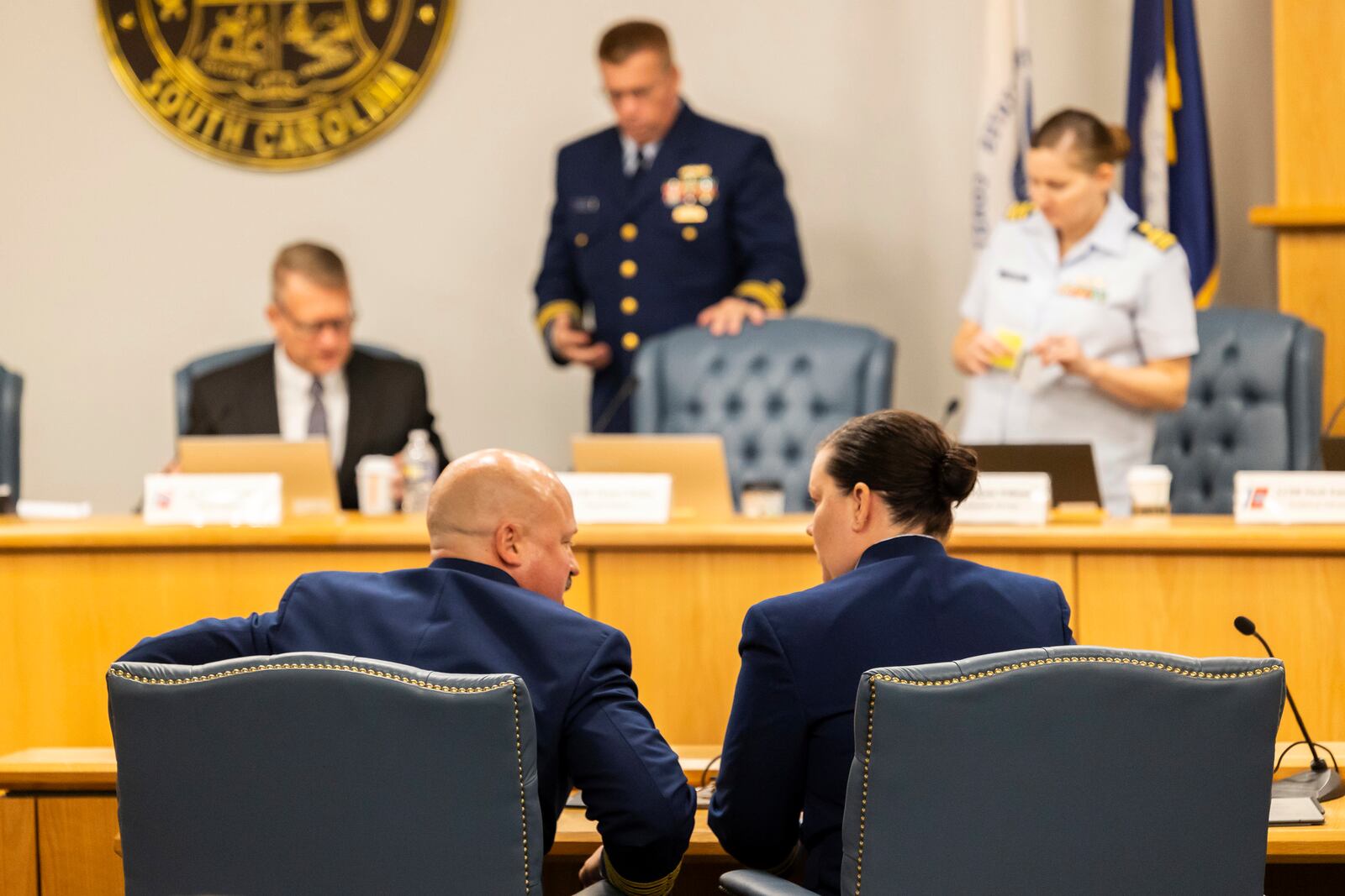 Captain Jamie Frederick, at left, with the U.S. Coast Guard Sector Boston, speaks with Coast Guard counsel during a break during the final day of the Coast Guard investigatory hearing on the causes of the implosion of an experimental submersible headed for the wreck of the Titanic, Friday, Sept. 27, 2024, in North Charleston, S.C. (AP Photo/Mic Smith)