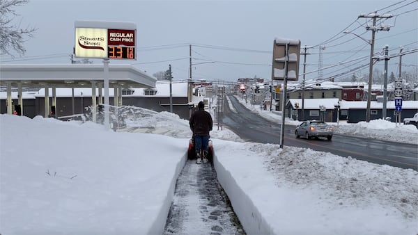 A person clears the snow from the sidewalk in Lowville, N.Y., on Saturday, Nov. 30, 2024. (AP Photo/Cara Anna)