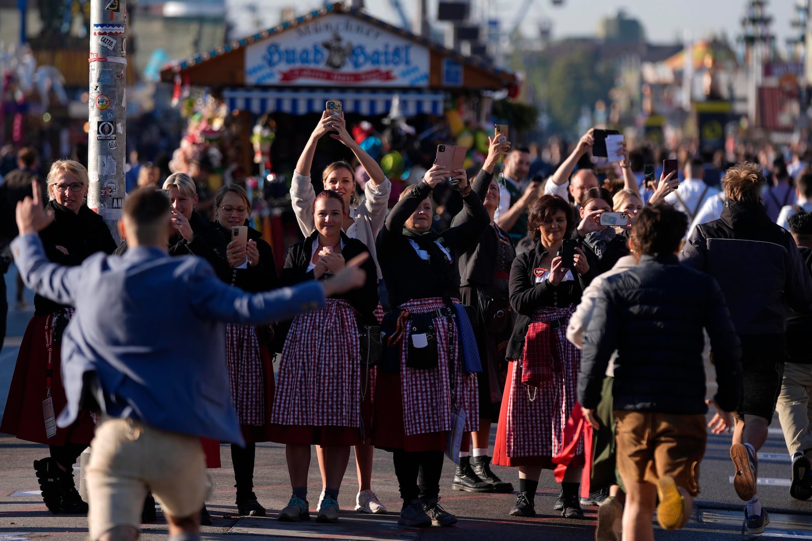 Waitresses film the opening start of the 189th 'Oktoberfest' beer festival in Munich, Germany, Saturday, Sept. 21, 2024. (AP Photo/Matthias Schrader)