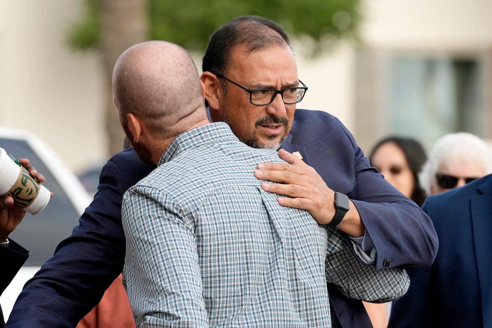 Adrian Fontes, right, Arizona Secretary of State, hugs Tim Stringham, the Democratic candidate for Maricopa County Recorder, as the two arrive to cast their votes on the first day of early in-person voting for the general election at Surprise City Hall Wednesday, Oct. 9, 2024, in Surprise, Ariz. (AP Photo/Ross D. Franklin)