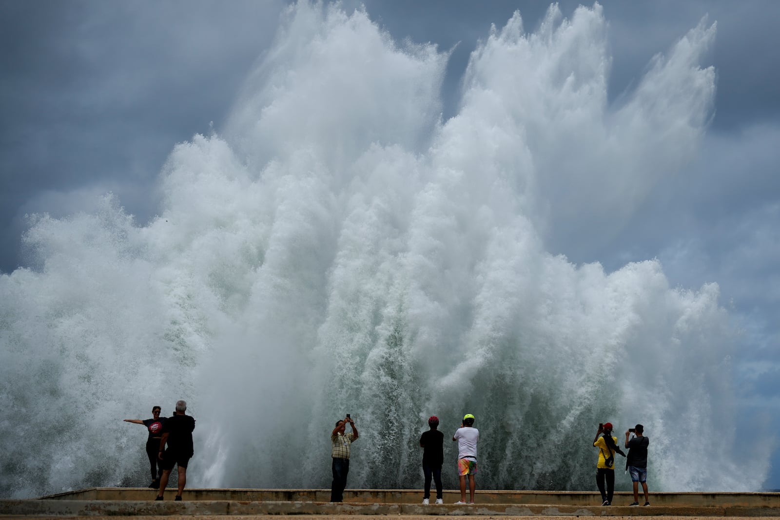 People take photos of the spray from waves crashing against the Malecon seawall, brought by the tail end of Hurricane Milton, in Havana, Cuba, Wednesday, Oct. 9, 2024. (AP Photo/Ramon Espinosa)