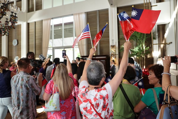 A woman waves Taiwanese and American flags as the Taiwan President Lai Ching-te arrives at the Kahala Hotel and Resort Saturday, Nov. 30, 2024 in Honolulu. (AP Photo/Marco Garcia)