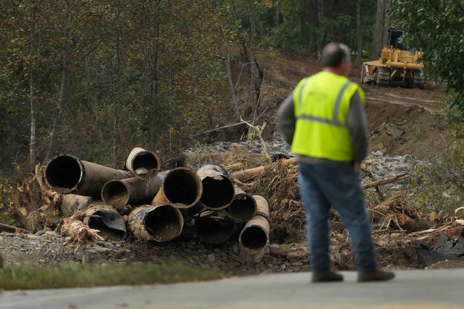 Electrical contract worker Matthew Tipton looks over the remnants of a waterline serving Asheville, N.C., downstream from North Fork Reservoir, a main source of water for the city, Wednesday, Oct. 2, 2024, after the line was destroyed during Hurricane Helene in Black Mountain, N.C. (AP Photo/Jeff Roberson)