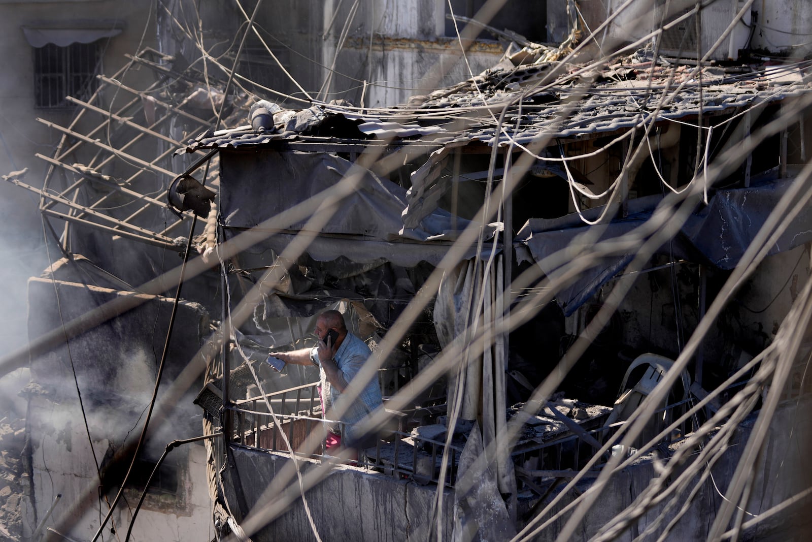 A man stands on the balcony of his destroyed house at the site of Israeli airstrikes that destroyed buildings facing the city's main government hospital in a densely-populated neighborhood, in southern Beirut, Lebanon, Tuesday, Oct. 22, 2024. (AP Photo/Hussein Malla)