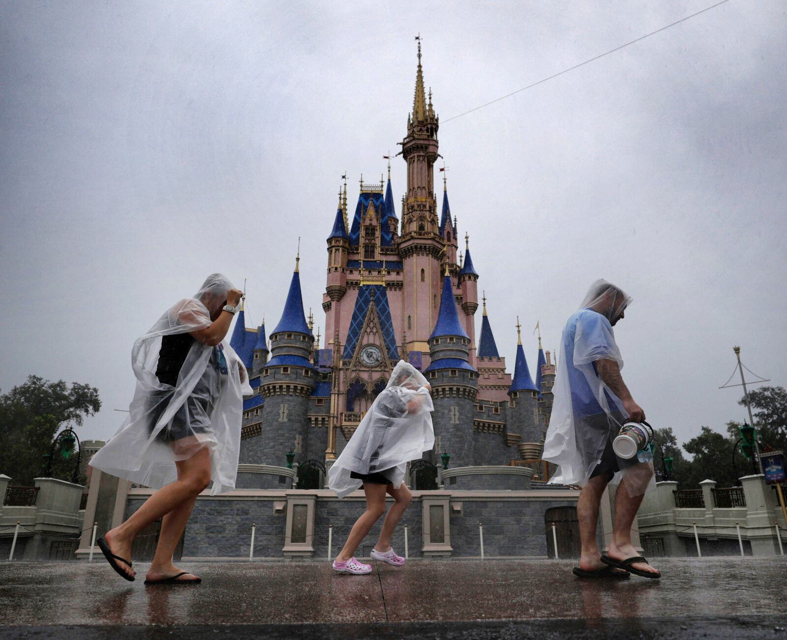 Guests weather early bands of rain from Hurricane Milton at the Magic Kingdom at Walt Disney World in Bay Lake, Fla., Wednesday, Oct. 9, 2024. All four of Disney's Florida theme parks closed early Wednesday due to the forecast track of the storm. (Joe Burbank/Orlando Sentinel via AP)