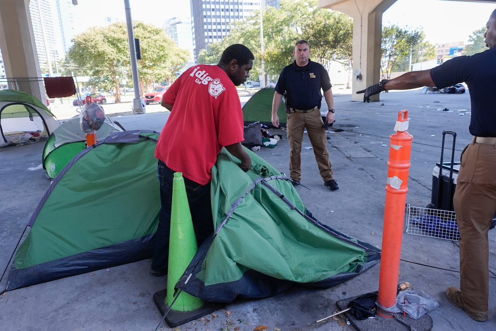 Louisiana State police give instructions to people living in a homeless encampment to move to a different pre-designated location as they perform a sweep in advance of a Taylor Swift concert in New Orleans, Wednesday, Oct. 23, 2024. (AP Photo/Gerald Herbert)