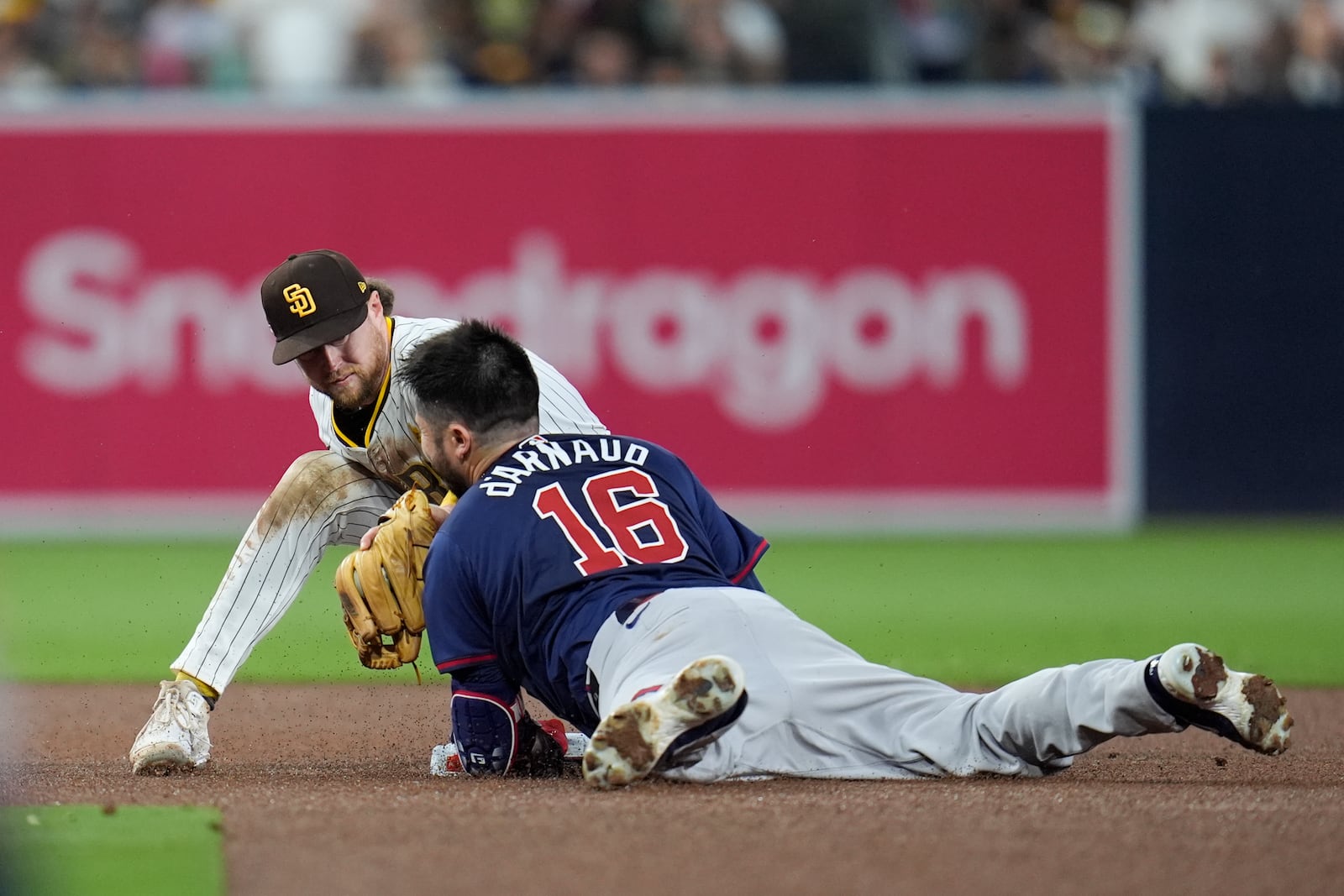 Atlanta Braves' Travis d'Arnaud (16) slides into second base with a double before the tag attempt from San Diego Padres second baseman Jake Cronenworth during the fourth inning in Game 1 of an NL Wild Card Series baseball game Tuesday, Oct. 1, 2024, in San Diego. (AP Photo/Gregory Bull)